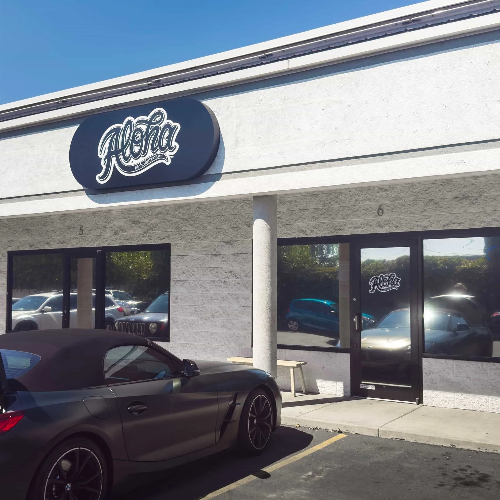 un bonito BMW aparcado delante de un estudio de tatuajes llamado Aloha Tattoos en Murray, utah.